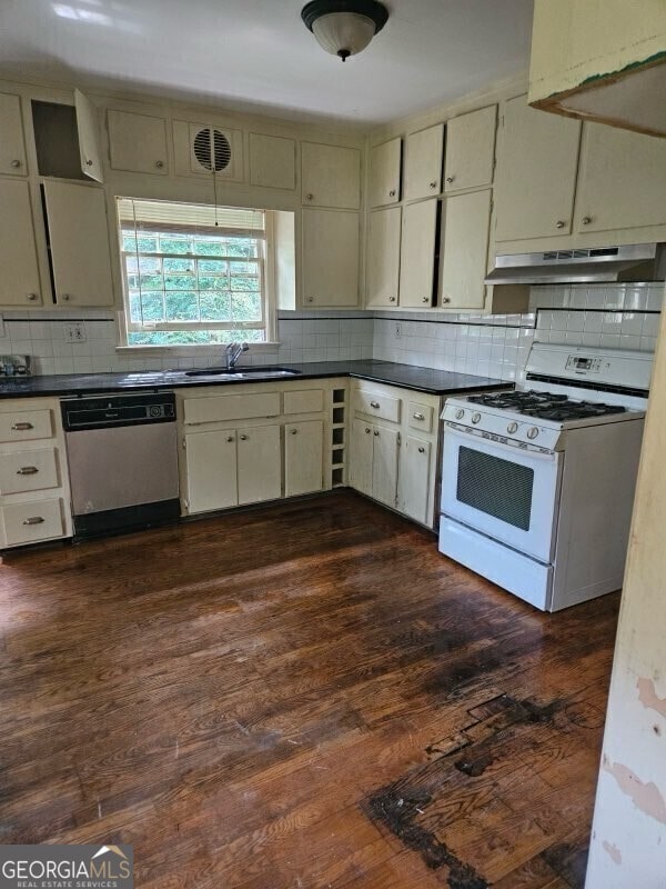 kitchen with dishwashing machine, white gas stove, under cabinet range hood, dark wood-style flooring, and a sink