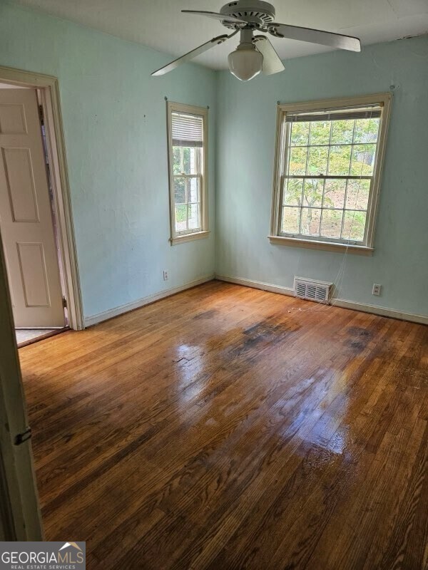 spare room featuring a ceiling fan, baseboards, visible vents, and hardwood / wood-style floors