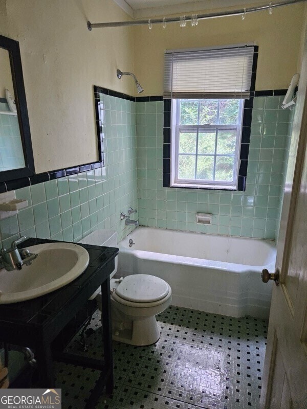 full bathroom with shower / bathtub combination, toilet, vanity, tile walls, and wainscoting