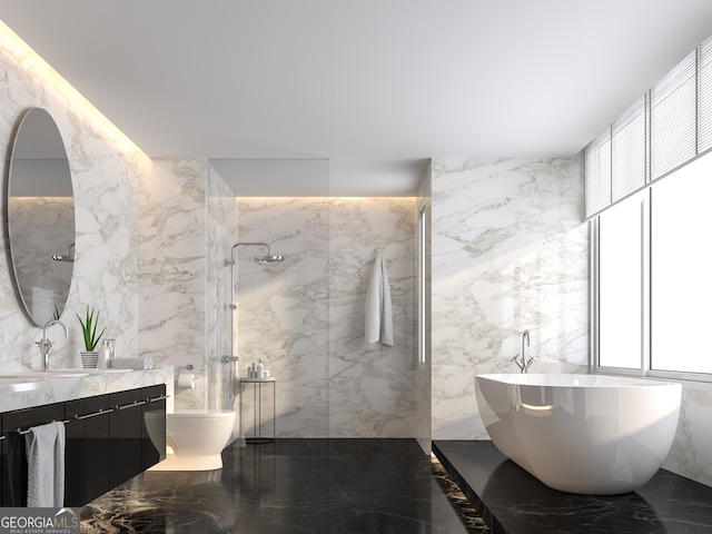 bathroom with marble finish floor, vanity, a marble finish shower, and stone wall