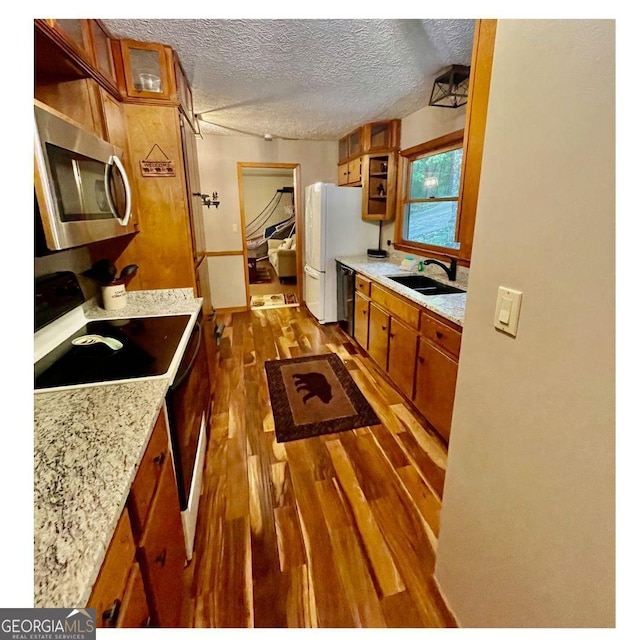 kitchen with range with electric cooktop, hardwood / wood-style floors, black dishwasher, sink, and light stone counters