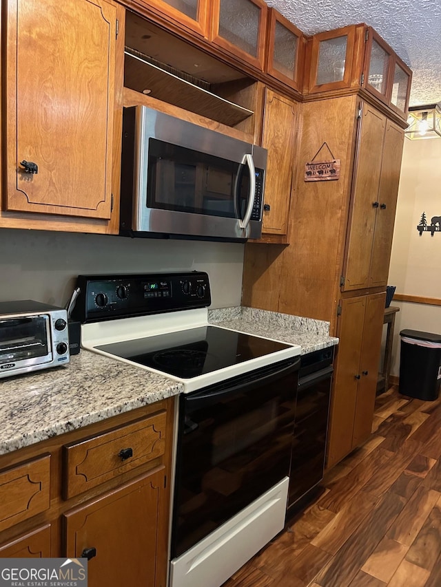 kitchen featuring dark hardwood / wood-style floors, light stone countertops, a textured ceiling, and electric range