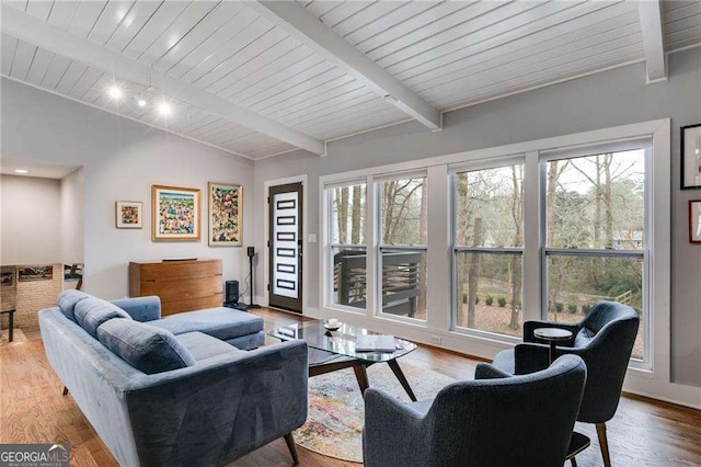 living room with a healthy amount of sunlight, lofted ceiling with beams, light hardwood / wood-style flooring, and wooden ceiling