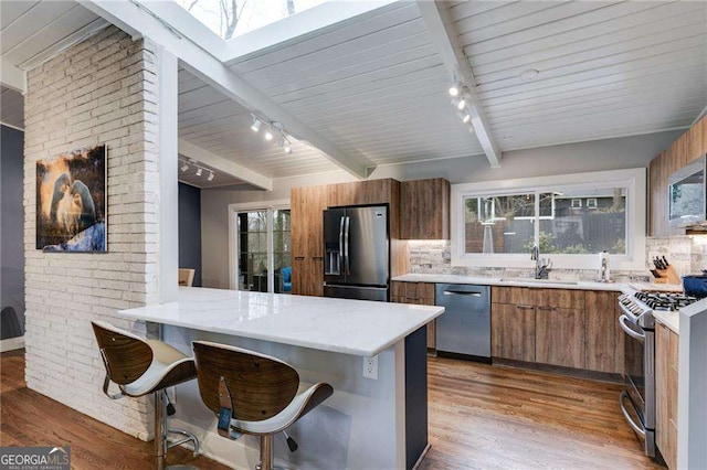 kitchen featuring dark wood-type flooring, sink, appliances with stainless steel finishes, a kitchen breakfast bar, and kitchen peninsula