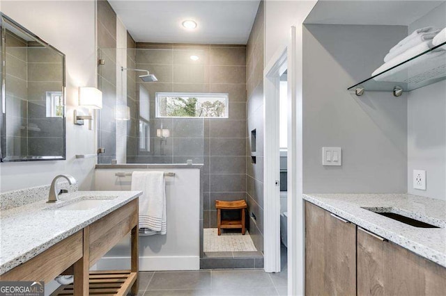 bathroom with vanity, toilet, tile patterned flooring, and a tile shower