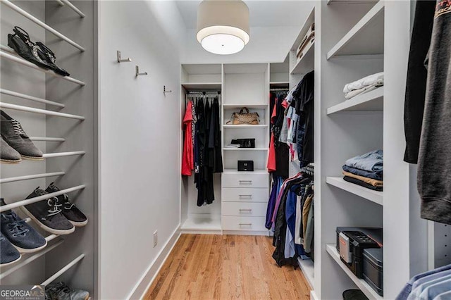 walk in closet with light hardwood / wood-style flooring