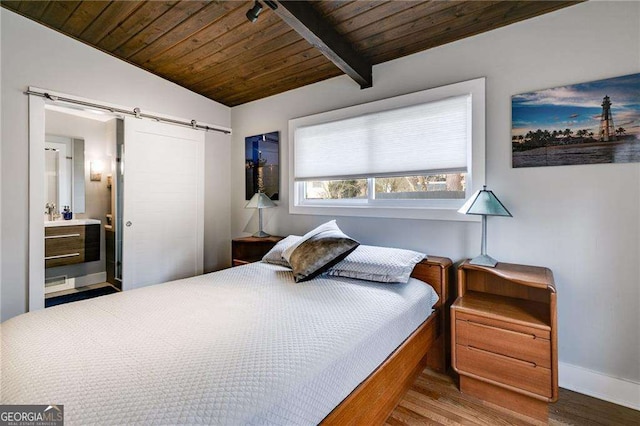 bedroom featuring ensuite bathroom, lofted ceiling with beams, wooden ceiling, a barn door, and hardwood / wood-style floors