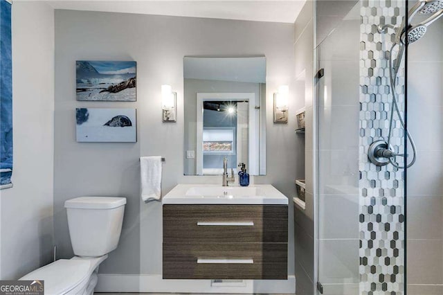 bathroom featuring vanity, a tile shower, and toilet