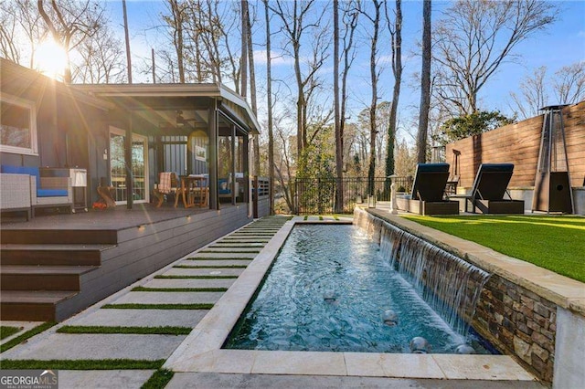 view of swimming pool featuring a wooden deck, a sunroom, and pool water feature