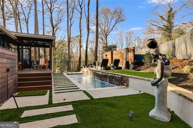 view of swimming pool featuring pool water feature, a deck, and a lawn