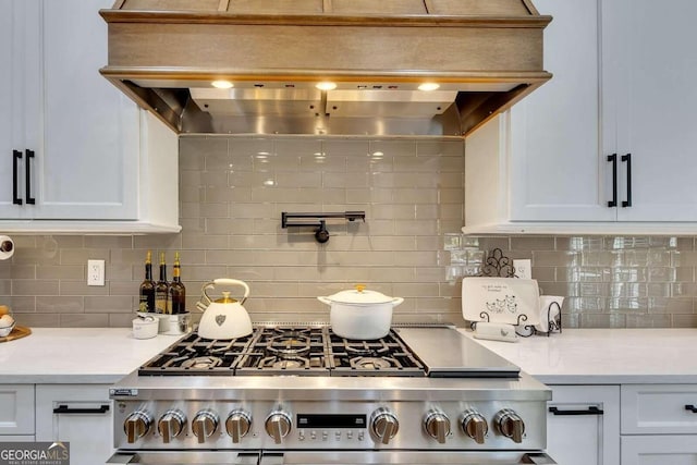 kitchen with white cabinetry, stainless steel range oven, and custom range hood