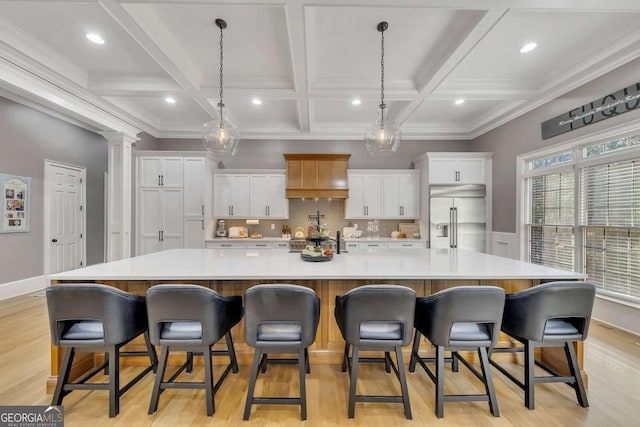 kitchen with white cabinetry, built in refrigerator, a breakfast bar, and a large island with sink