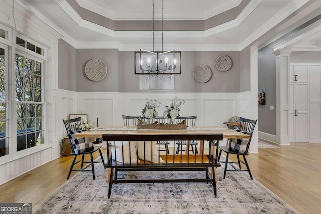 dining room featuring crown molding, an inviting chandelier, light hardwood / wood-style floors, and a tray ceiling