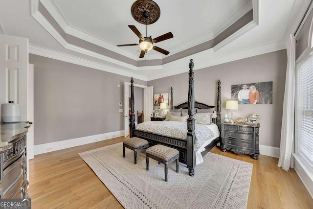 bedroom featuring multiple windows, a tray ceiling, and light hardwood / wood-style floors