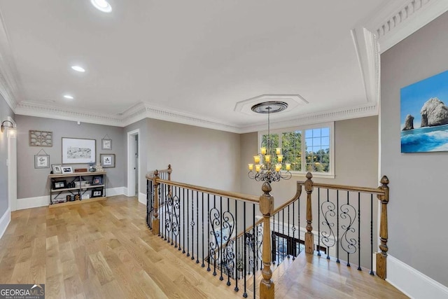 corridor featuring crown molding, an inviting chandelier, and light hardwood / wood-style floors