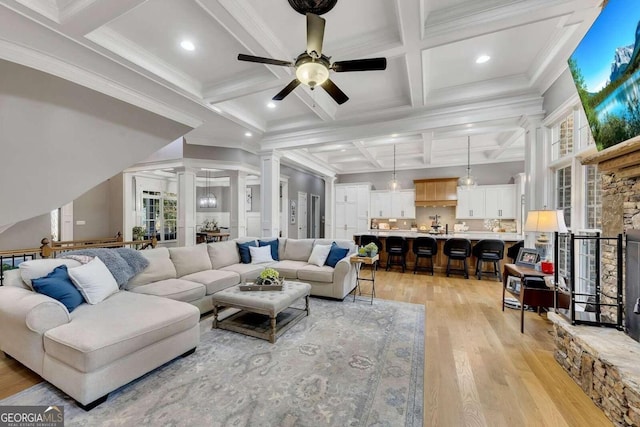 living room with coffered ceiling, decorative columns, beamed ceiling, ceiling fan, and light hardwood / wood-style floors