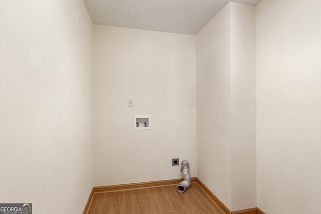 clothes washing area featuring electric dryer hookup, hookup for a washing machine, wood-type flooring, and a textured ceiling