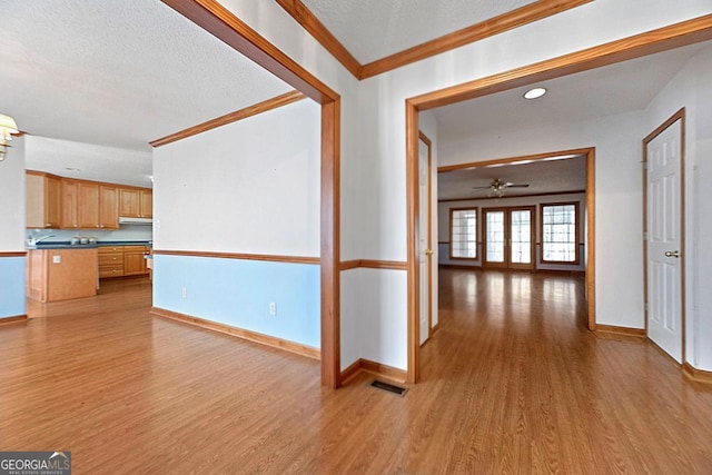 unfurnished living room featuring light hardwood / wood-style flooring, ornamental molding, and a textured ceiling