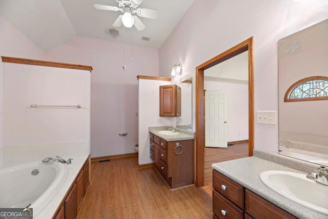 bathroom featuring lofted ceiling, a relaxing tiled tub, vanity, hardwood / wood-style flooring, and ceiling fan