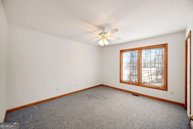 carpeted empty room with ceiling fan and a textured ceiling