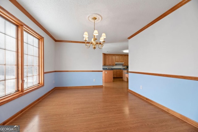 interior space featuring crown molding, a textured ceiling, a chandelier, and light hardwood / wood-style floors