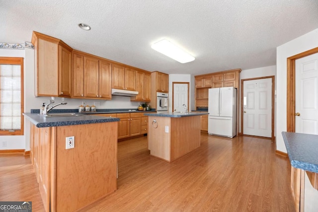 kitchen featuring white appliances, sink, a kitchen island, and light hardwood / wood-style flooring