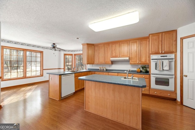 kitchen with sink, white appliances, a center island with sink, kitchen peninsula, and light wood-type flooring