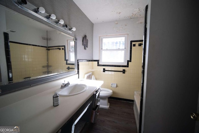 full bathroom featuring toilet,  shower combination, tile walls, vanity, and hardwood / wood-style flooring