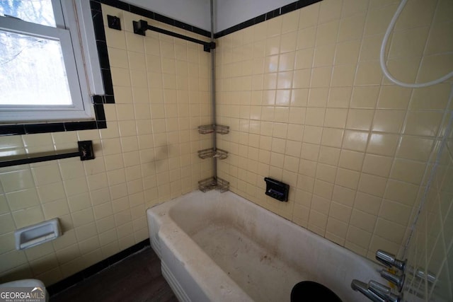 bathroom with tiled shower / bath combo and tile walls