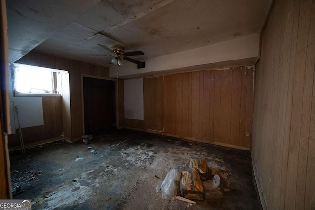 misc room featuring ceiling fan and wood walls