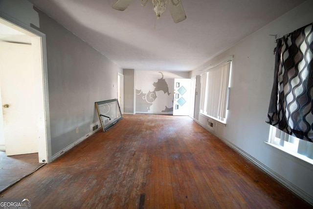 unfurnished living room featuring dark wood-type flooring and ceiling fan