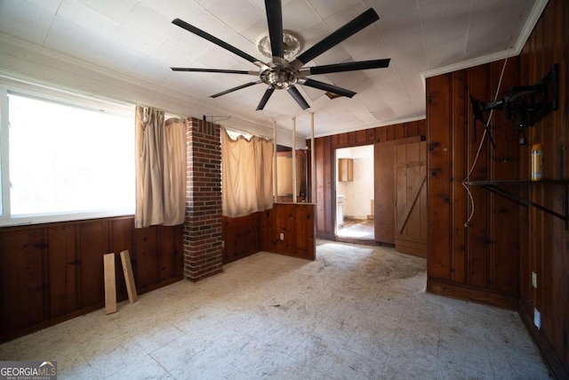 unfurnished bedroom with ceiling fan, ornamental molding, and wooden walls