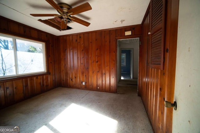 spare room featuring ceiling fan, crown molding, light colored carpet, and wooden walls