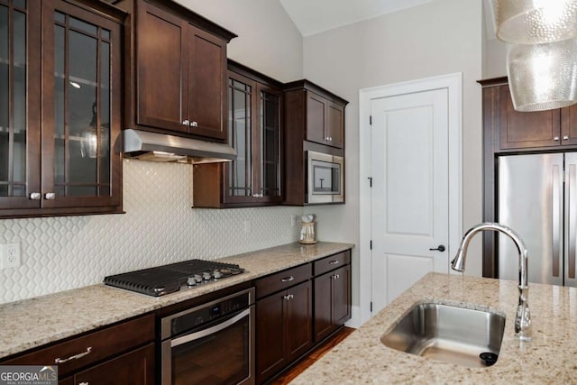 kitchen with sink, backsplash, light stone counters, dark brown cabinetry, and stainless steel appliances