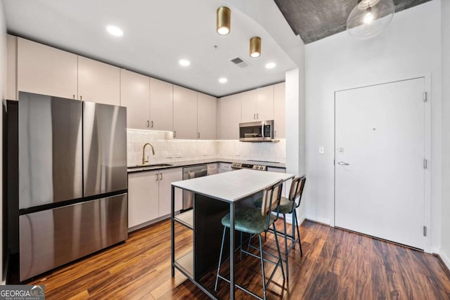 kitchen with stainless steel appliances, sink, a kitchen bar, and dark hardwood / wood-style floors