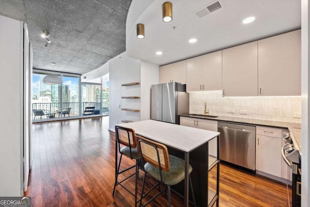 kitchen with white cabinetry, a breakfast bar area, wood-type flooring, and appliances with stainless steel finishes