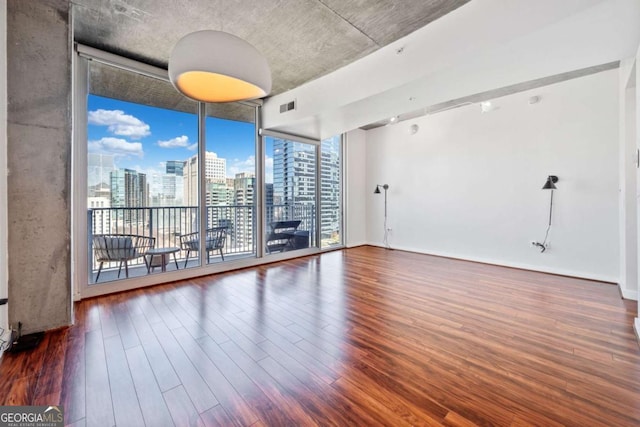 spare room with dark hardwood / wood-style flooring and a wall of windows