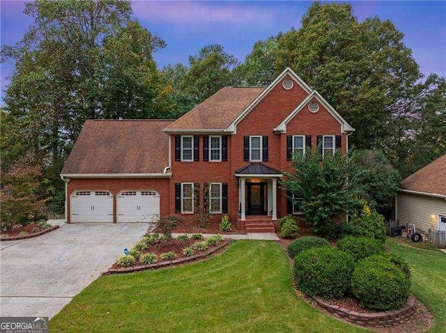 colonial home with a garage and a yard