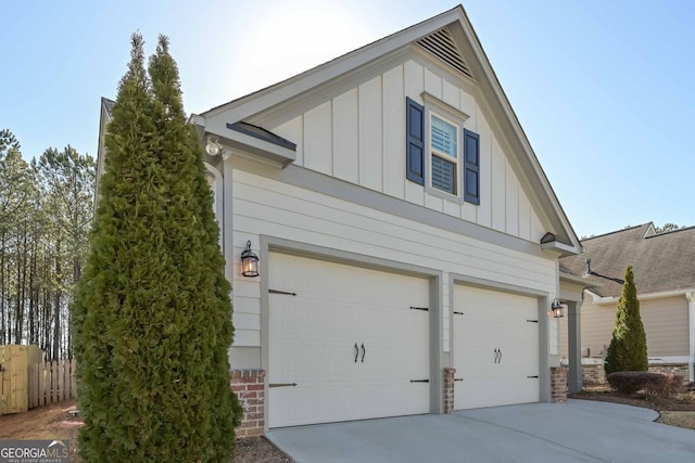 view of home's exterior featuring board and batten siding, driveway, a garage, and fence