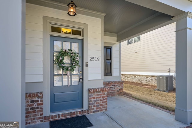 view of exterior entry with a porch and central AC unit