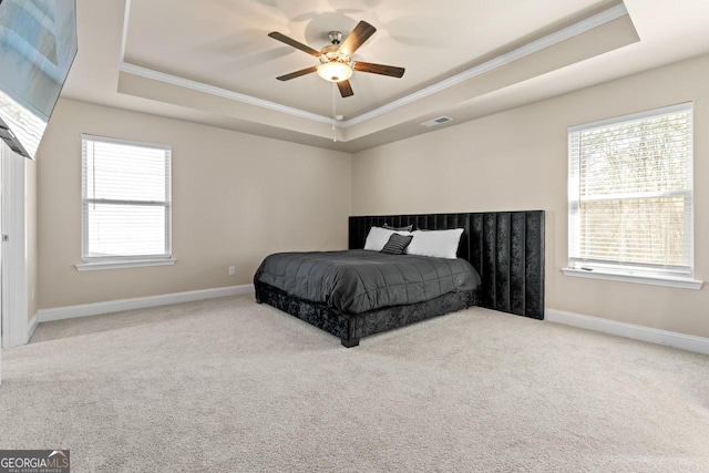 carpeted bedroom with a raised ceiling, ornamental molding, and ceiling fan