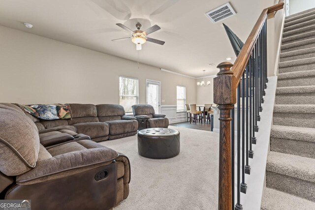 carpeted living room featuring ceiling fan with notable chandelier