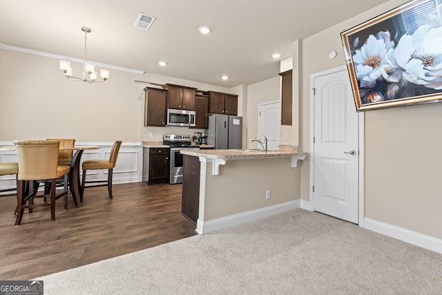 kitchen featuring appliances with stainless steel finishes, decorative light fixtures, a chandelier, a kitchen breakfast bar, and dark brown cabinetry