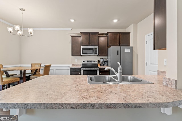 kitchen with crown molding, appliances with stainless steel finishes, sink, and a breakfast bar area