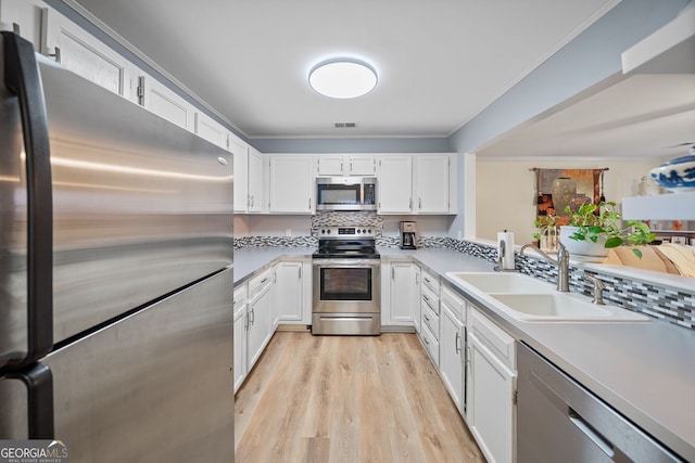 kitchen with sink, crown molding, stainless steel appliances, and white cabinets