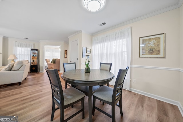 dining space featuring ornamental molding, plenty of natural light, and light hardwood / wood-style flooring