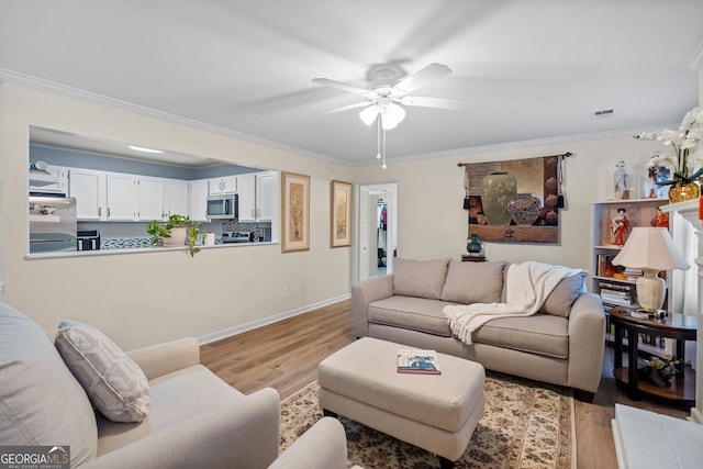 living room with ceiling fan, ornamental molding, and light wood-type flooring