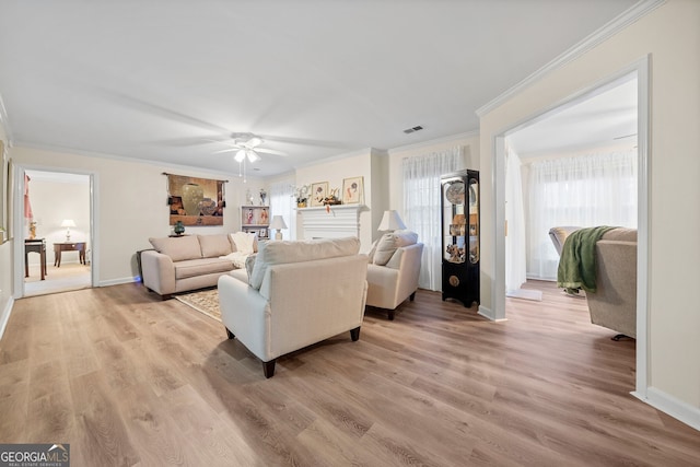 living room featuring crown molding, ceiling fan, and light wood-type flooring