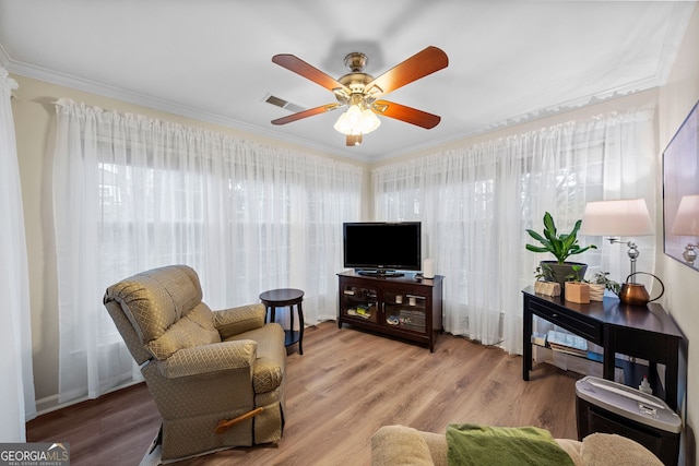 living area with hardwood / wood-style flooring, ornamental molding, and ceiling fan