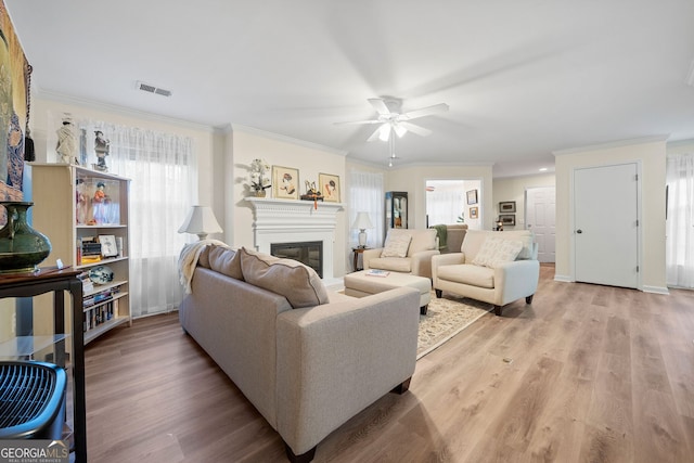 living room with hardwood / wood-style flooring, crown molding, and ceiling fan